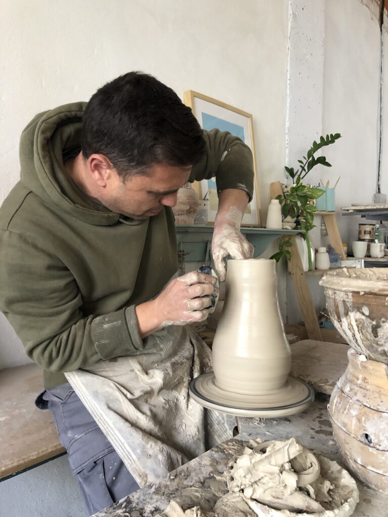 Potter throwing a white clay vase on the wheel